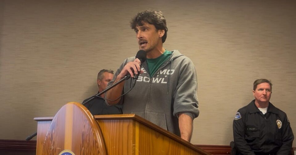Assembly District 72 candidate Chris Kluwe speaks at a wooden podium with the City of Huntington Beach seal.